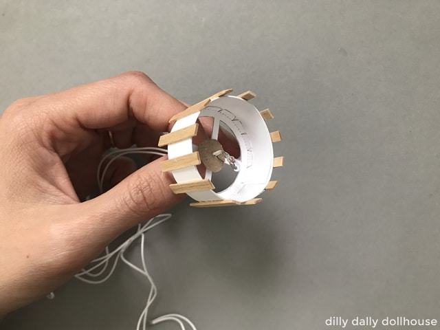 dollhouse light bulb inserted into the miniature pendant frame