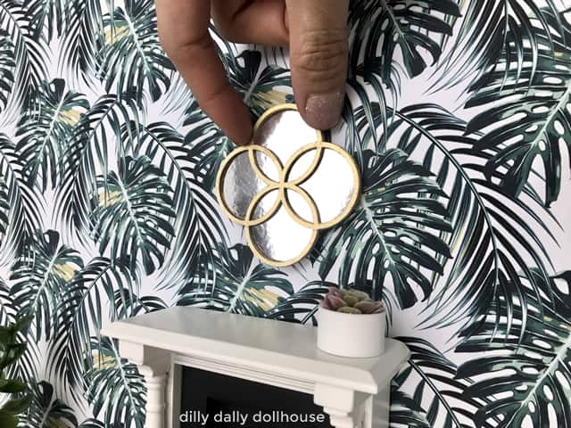 miniature gold round mirror above a dollhouse fireplace
