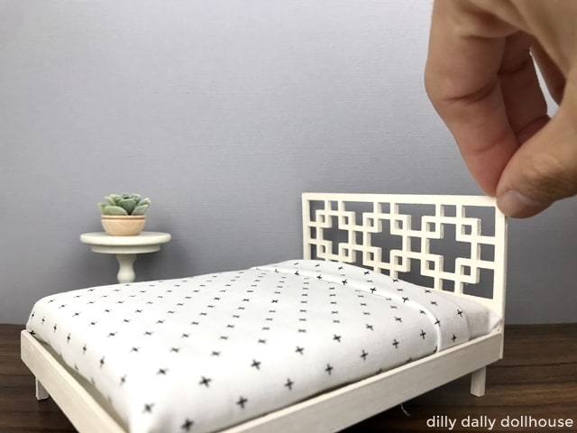 miniature dollhouse bed held by hand